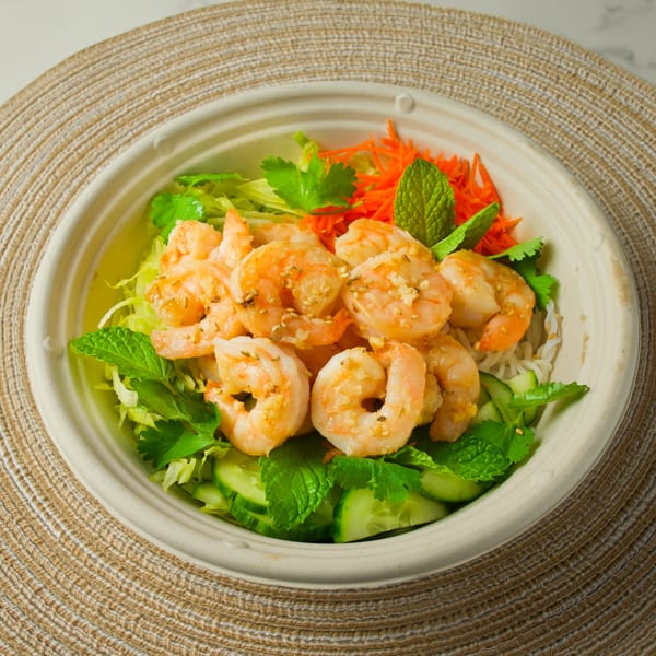 A Vietnamese shrimp bowl with noodles, lettuce, carrots, cucumbers, cilantro, and mint.