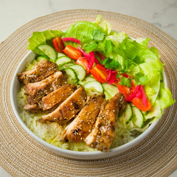 CUON Vietnamese Fresh Rolls' grilled chicken rice bowl with lettuce, cucumbers, tomatoes, and pickled onions.