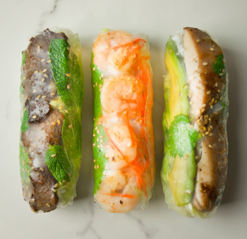 Three CUON Vietnamese fresh rolls, one with beef and mint, one with shrimp and carrots, and one with chicken and avocado.